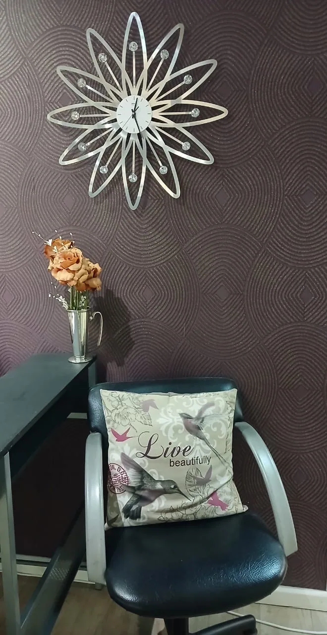 A salon styling chair with a Live beautifully cushion beneath a decorative clock